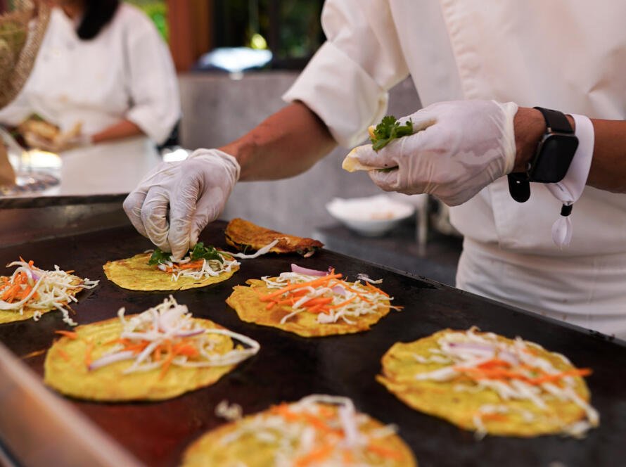 Chef preparing colorful pancakes on grill.