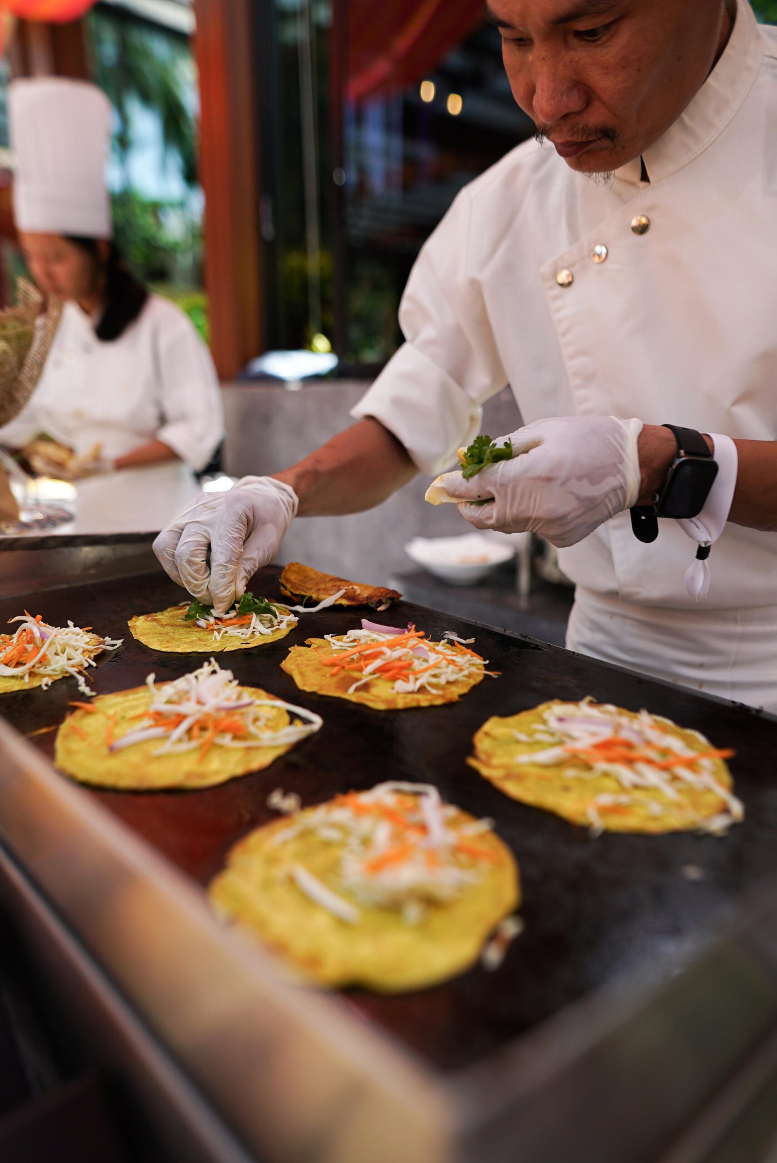 Chef preparing colorful pancakes on grill.